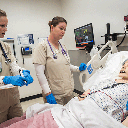 Nursing students simulating on test dummy in hospital bed