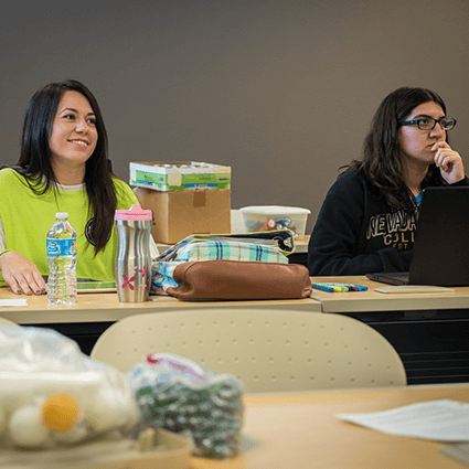 Two students in back of the classroom paying attention to lecture