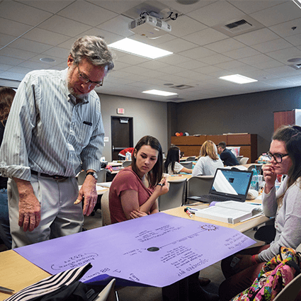 Education Professor, Dr. Lawrence Rudd looking at students' work