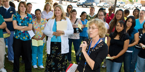 Group of students listening to female speaker outside with microphone