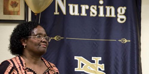 Woman standing in front of a Nevada State nursing banner.