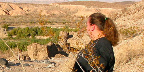 Picture of a woman looking out into the valley from a mountain.