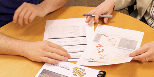 Picture of two people looking over some documents.