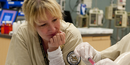 Nevada State nursing student observing someone extracting liquid from a vile with a syringe.