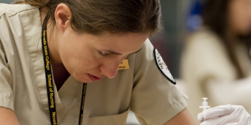 Close up of a female Nevada State nursing student focused on a procedure.