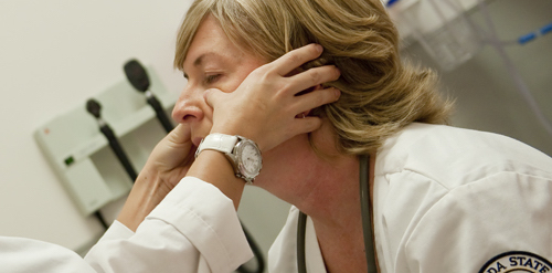 Close up of a nursing student palpating the eye area of another nursing student.