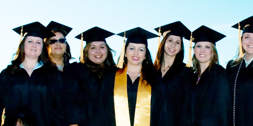 Female graduating students looking at camera standing in cap and gownsn