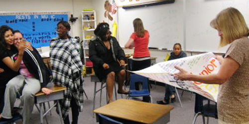 Teacher looking at a bunch of signatures on large piece of paper in classroom with students