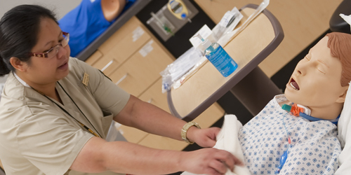 Nursing student practicing on dummy to use as hospital patient