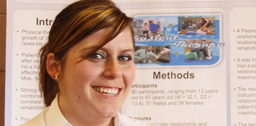 Female looking at camera standing in front of large poster with research on it