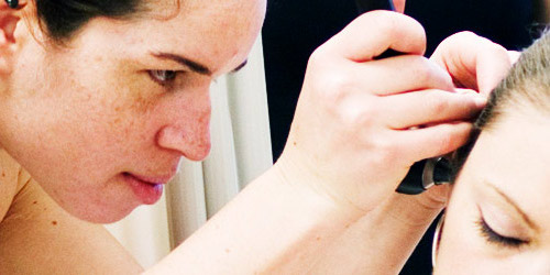 Woman examining inside of another woman's ear with medical instrument