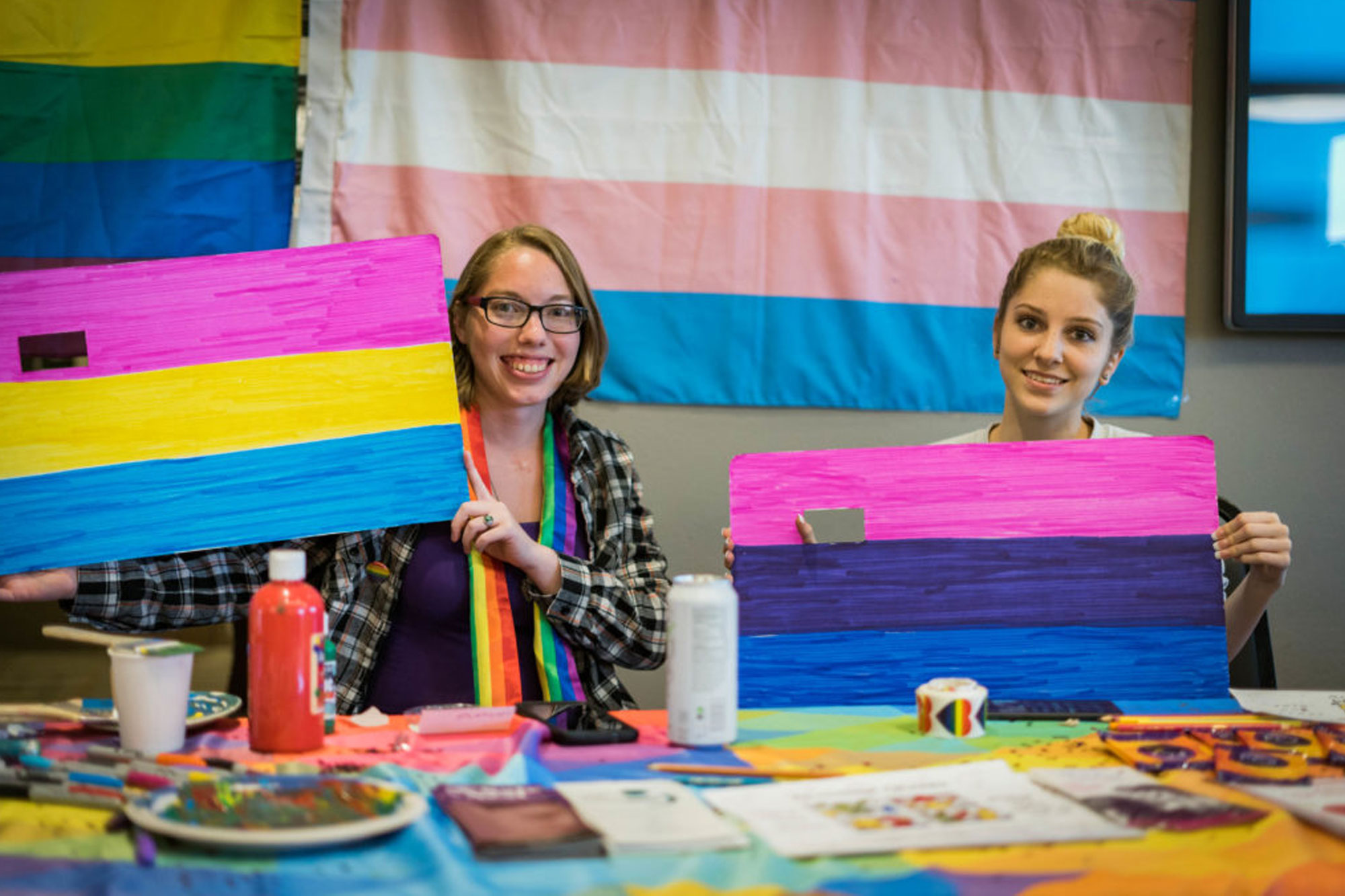 Picture of two female students holding up painted flags for different sexual and gender identities