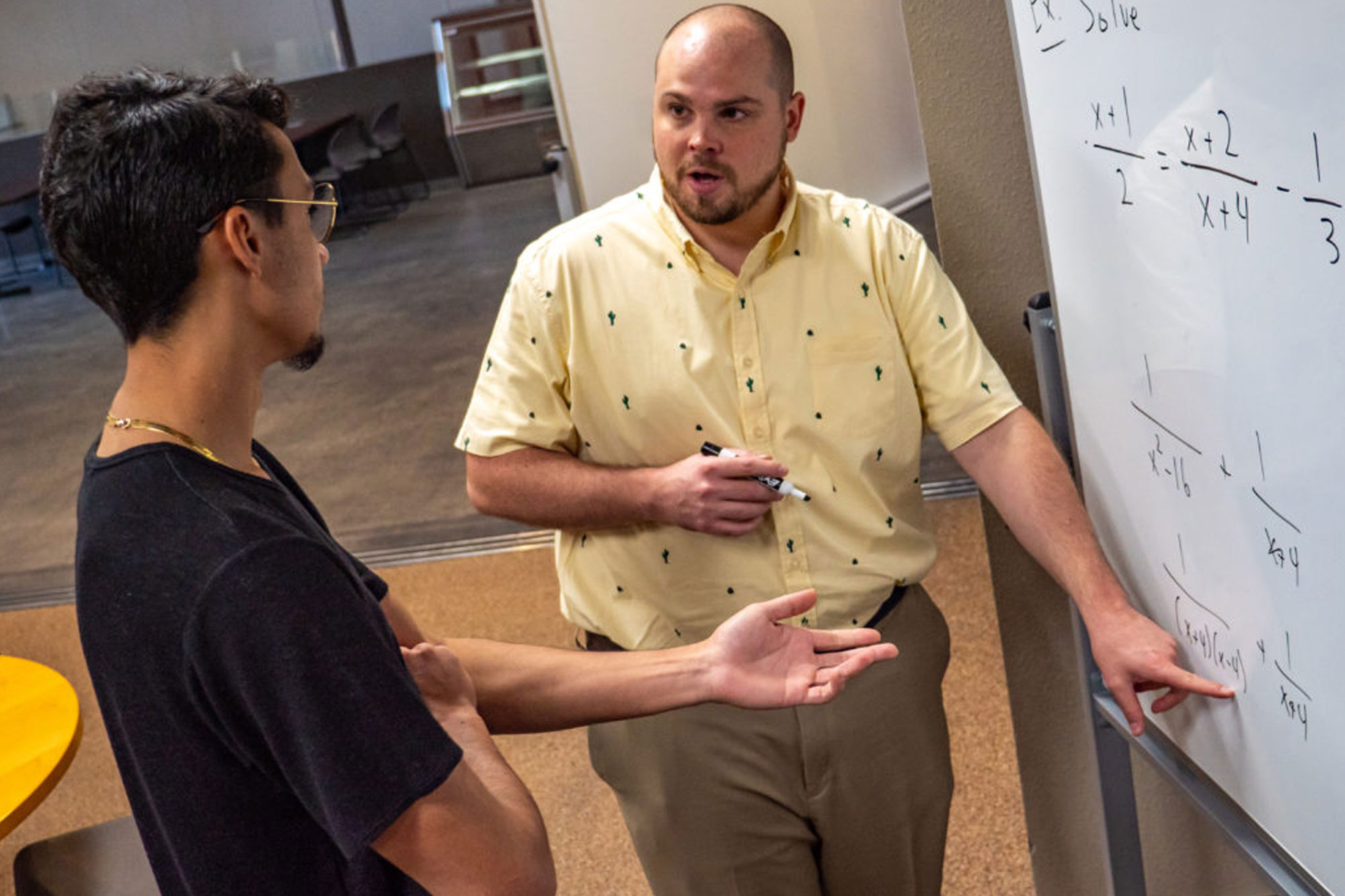 Tutor pointing to math equations on white board and talking to student