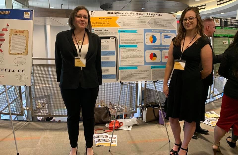 Two female students standing in front of their poster presenting at research conference