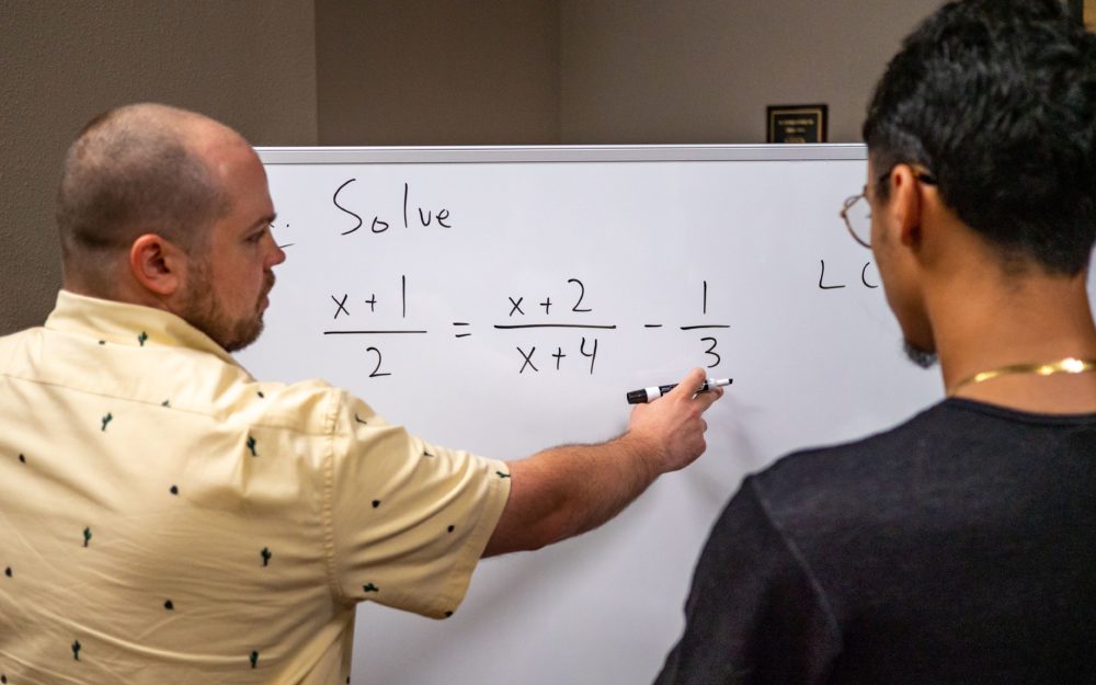 tutor working with student on white board on mac equations