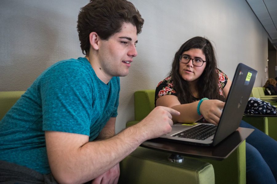 Two students working on laptop together