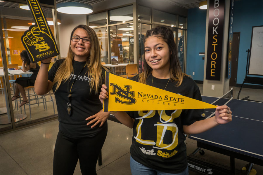 Two students with NSC shirts on holding up NSC pendants and props