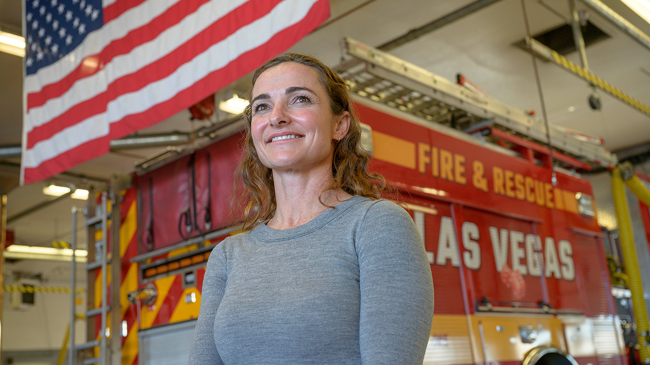 Woman smiling in front of US Flad and Las Vegas Fire & Rescue truck